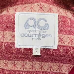 May include: Close-up of a pink and red fabric with a white label. The label features the text "AC sport futur courr&egrave;ges paris" in blue and white. The number "9" is printed below the label.