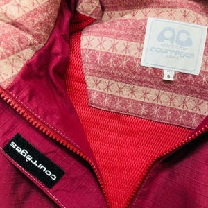 May include: Close-up of a magenta jacket with a zipper and a label that says "courr&egrave;ges". The interior lining is patterned with a pink and beige design. A white label with the text "AC sport futur courreges paris" is visible.