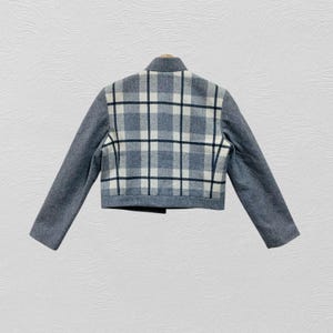 K&ouml;nnte beinhalten: Kurze Jacke in Grau mit kariertem R&uuml;ckenteil. Das Karomuster zeigt graue, schwarze und wei&szlig;e Quadrate. Die Jacke hat einen hohen Kragen und lange &Auml;rmel. Die &Auml;rmel sind einfarbig grau.