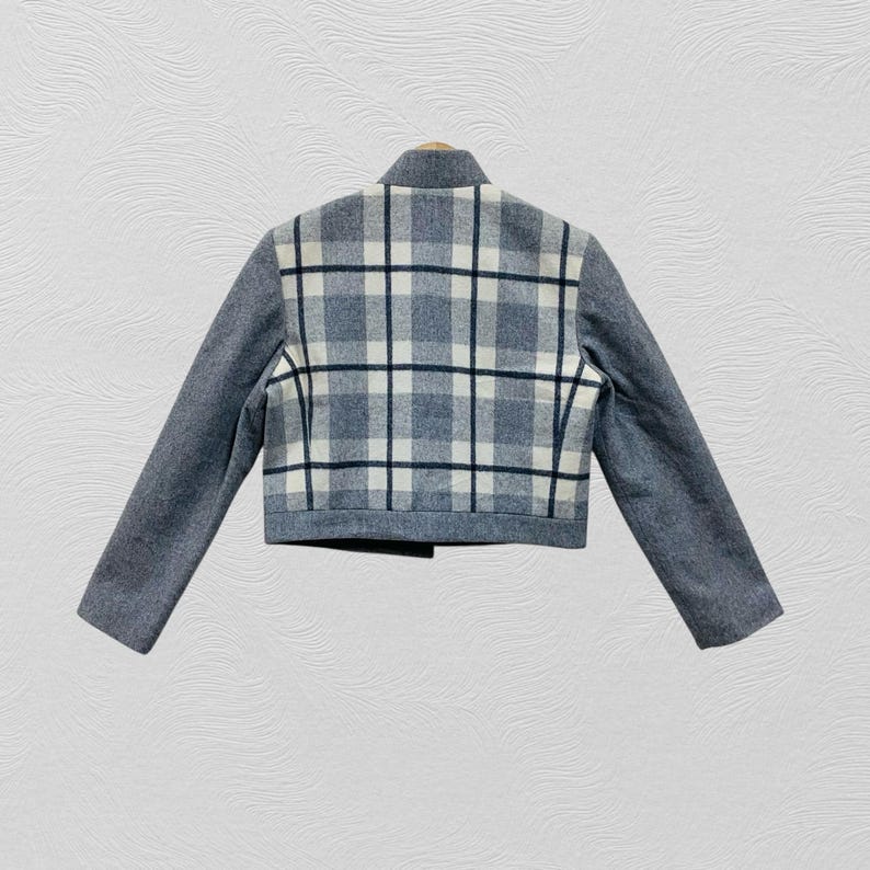 K&ouml;nnte beinhalten: Kurze Jacke in Grau mit kariertem R&uuml;ckenteil. Das Karomuster zeigt graue, schwarze und wei&szlig;e Quadrate. Die Jacke hat einen hohen Kragen und lange &Auml;rmel. Die &Auml;rmel sind einfarbig grau.