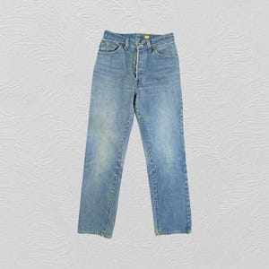 Puede incluir: Un par de pantalones vaqueros de mezclilla azul claro con cierre de botón y cinco bolsillos.