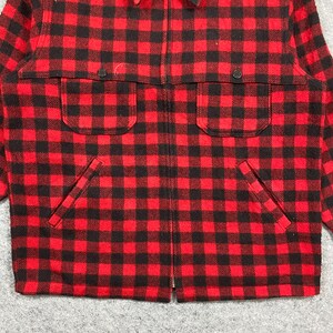 Op de afbeelding: Rood-zwarte geruite jas met een volledige ritssluiting. De jas heeft twee borstzakken en twee lagere zakken. De stof is een dik, geweven materiaal. De jas heeft een klassieke, outdoor-stijl.