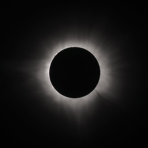 Peut inclure: Une éclipse solaire totale, avec la couronne du soleil visible comme un halo lumineux autour de la silhouette noire de la lune.