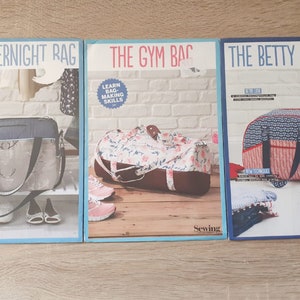 Puede incluir: Tres patrones de costura para bolsos, cada uno con un diseño diferente. El primer patrón es para un bolso de viaje con un diseño marrón y azul, el segundo es para un bolso de gimnasio con un diseño floral, y el tercero es para un bolso Betty Bowler con un diseño rojo y azul. Cada patrón incluye instrucciones para hacer el bolso y tiene el texto "Aprende a hacer bolsos" o "¡Impulsa tus habilidades de costura!"
