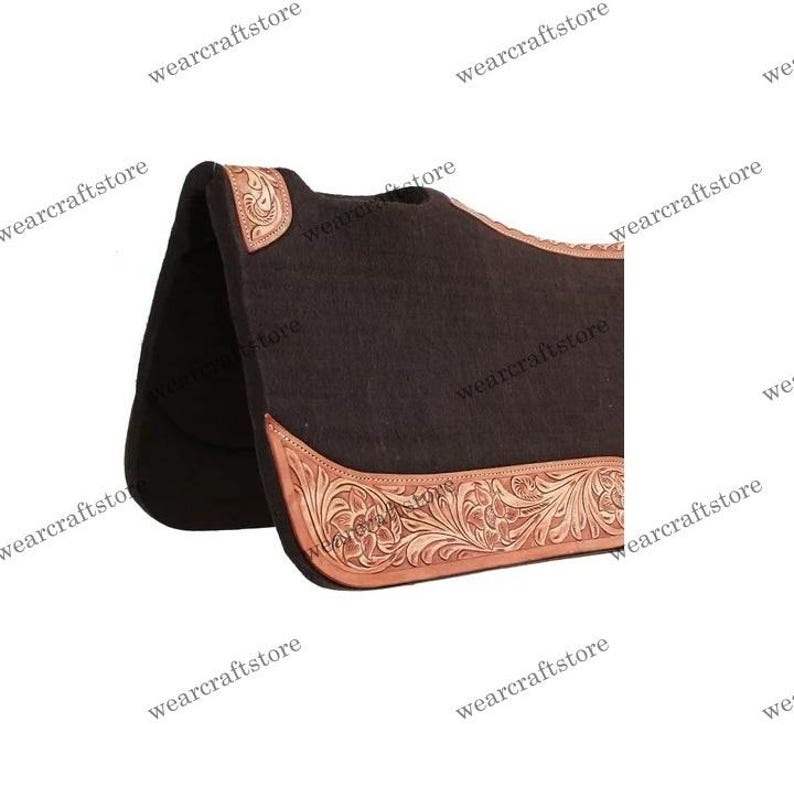Puede incluir: Un protector de silla de montar marr&oacute;n oscuro con un borde y esquinas de cuero repujado de color marr&oacute;n claro. El cuero presenta un dise&ntilde;o floral. La almohadilla est&aacute; dise&ntilde;ada para uso ecuestre.
