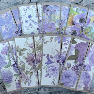 May include: A set of 12 purple floral bookmark cards with a rustic brown paper background. Each card has a different floral design with purple flowers and green leaves. The cards are tied together with a purple string.