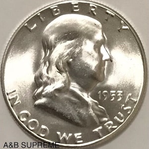 May include: Silver US half dollar coin with the profile of Benjamin Franklin and the inscription "LIBERTY" above his head. The coin also features the inscription "IN GOD WE TRUST" and the year "1953".
