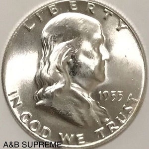 May include: A silver 1955 United States Half Dollar coin featuring a profile of Benjamin Franklin with the inscription "LIBERTY" above and "IN GOD WE TRUST" below.