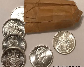 May include: A collection of Canadian coins, including 50-cent pieces and other denominations, are displayed. The coins are silver in color and feature images of Queen Elizabeth II and the Canadian coat of arms. A brown paper package is also present.