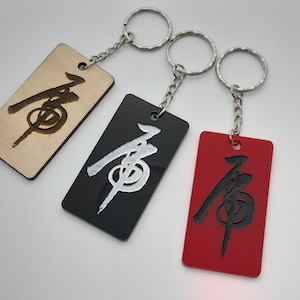 May include: Three keychains with the Chinese character "有" (meaning "have") engraved on them. The keychains are made of wood, black acrylic, and red acrylic.
