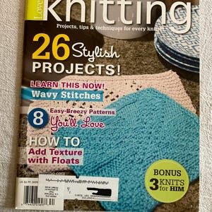 May include: A magazine cover titled "Love of Knitting" with the text "26 Stylish Projects!" and "13 Sassy Spring Sweaters." It features a teal knitted square and a beige knitted piece. The cover also includes the text "Bonus 3 Knits for Him."