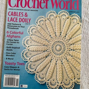 May include: A copy of Crochet World magazine featuring a cream-colored, crocheted doily. The magazine cover is blue with the title "Crochet World" in large pink letters. The cover also includes text about crochet projects and patterns.