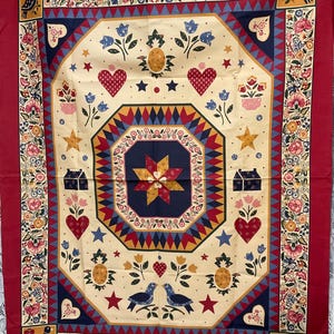 May include: A decorative quilt with a central octagonal design featuring a starburst pattern in navy, yellow, and red. The quilt has a cream-colored background with hearts, stars, birds, and floral motifs. The border is red with floral and bird designs.
