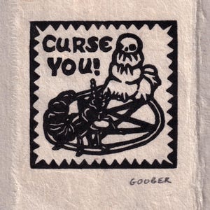 May include: A black and white linocut print featuring the words "CURSE YOU!" and a skull-like figure above a pentagram. The print has a jagged border and the artist's signature "GOOBER" at the bottom.