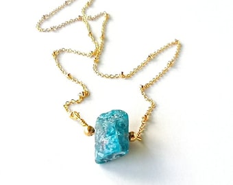 May include: A gold chain necklace with a single, large, blue-green gemstone pendant.