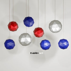 May include: Nine geometric paper sphere ornaments hanging from the ceiling. Three are red, three are blue, and three are silver.