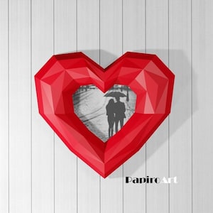 May include: Red origami heart-shaped frame with a black and white photo of a couple walking under an umbrella. The frame is on a white wood background. The text "PapiroArt" is at the bottom of the frame.