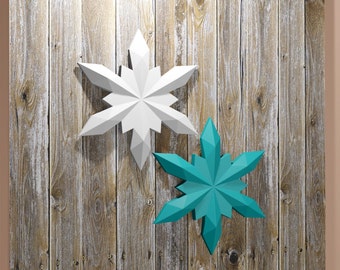 May include: Two paper snowflakes, one white and one teal blue, are attached to a weathered wood wall.