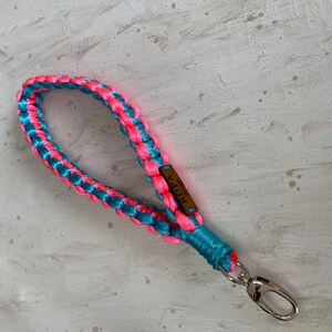 May include: A pink and teal braided dog lead with a brown leather tag that says "ROPA" and a silver clip.