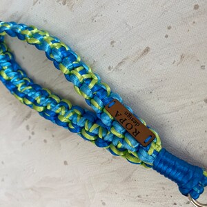 May include: A blue and green braided key chain with a brown leather tag that says "ROPA design".