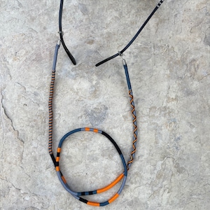 May include: A pair of glasses with a blue and orange braided cord. The cord is attached to the glasses with metal clasps.