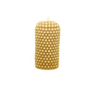 May include: A beige pillar candle with a textured surface made of small, round bumps.