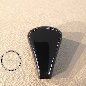 Könnte beinhalten: Schwarzer Schaltknauf mit glatter, glänzender Oberfläche.