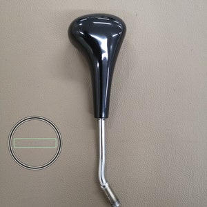 Puede incluir: Pomo de palanca de cambios de plástico negro con base de metal cromado. El pomo tiene forma de lágrima y un acabado brillante.