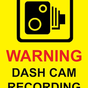 Puede incluir: Un letrero amarillo con un icono de cámara negro dentro de un rectángulo negro. La palabra "WARNING" está en rojo, y debajo, las palabras "DASH CAM RECORDING" están en negro, todo sobre un fondo amarillo.