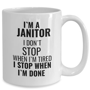 Peut inclure: Mug en céramique blanche avec une grande anse. Le mug présente le texte "I'M A JANITOR I DON'T STOP WHEN I'M TIRED I STOP WHEN I'M DONE" en lettres noires grasses. Le mug est conçu pour les boissons chaudes.