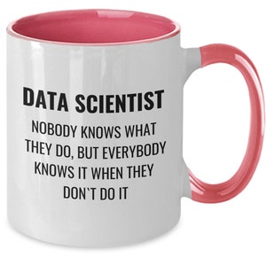 Puede incluir: Taza de cerámica blanca con interior y asa rosas. La taza presenta el texto "DATA SCIENTIST" sobre la cita: "NADIE SABE LO QUE HACEN, PERO TODO EL MUNDO LO SABE CUANDO NO LO HACEN."