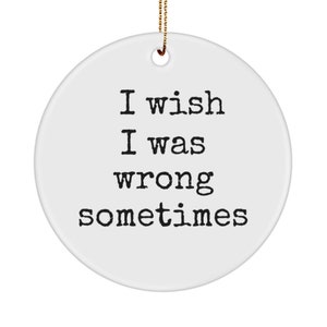 Può includere: Un ornamento rotondo in ceramica bianca con la scritta "I wish I was wrong sometimes" in nero. Ha un cordino dorato per appenderlo e un piccolo foro in alto.