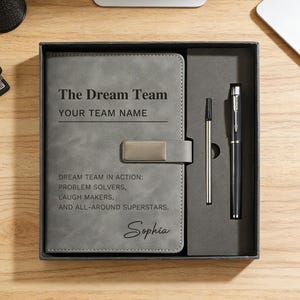 以下が含まれることがあります： グレーのノートセット、ペンと鉛筆付き。「The Dream Team」と「YOUR TEAM NAME」の文字が入ったノート。その下に「DREAM TEAM IN ACTION: PROBLEM SOLVERS, LAUGH MAKERS, AND ALL-AROUND SUPERSTARS. Sophia」と書かれています。