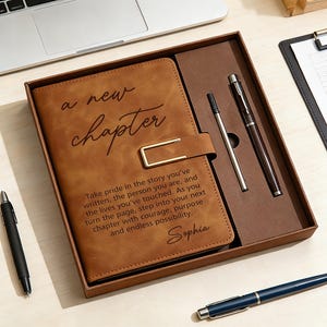 May include: A brown leather journal set with a pen and pencil. The journal cover reads "a new chapter" with an inspirational quote and the name "Sophia". The set is in a brown box, ideal for gifting.
