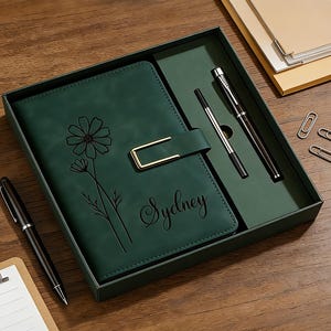 Puede incluir: Un juego de diario verde oscuro con un bol&iacute;grafo a juego y un bol&iacute;grafo plateado, presentado en una caja de regalo. El diario presenta un dise&ntilde;o floral y el nombre "Sydney" grabado en la portada. Incluye clips.