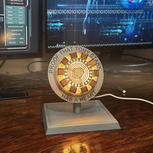 May include: A 3D printed replica of the Arc Reactor from the Iron Man films. The reactor is lit up and has the words "Proof that Tony Stark has a heart" inscribed around it.