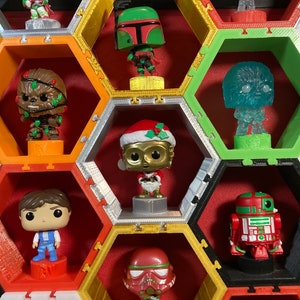 May include: A hexagonal shelf unit with various Star Wars themed figurines. The figurines include Chewbacca, Boba Fett, R2-D2, C-3PO, and a Christmas-themed C-3PO.