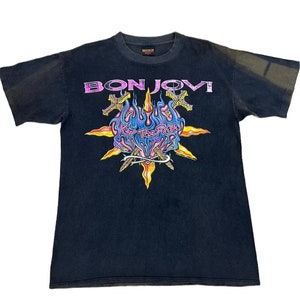 Peut inclure: T-shirt noir avec un graphique de croix enflammée et le texte "Bon Jovi" et "Keep The Faith".