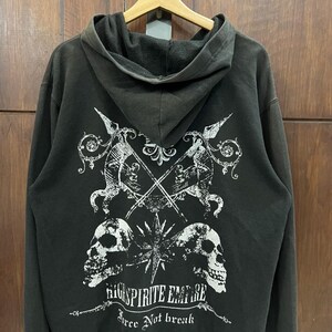 May include: Black hooded sweatshirt with a white graphic design on the back. The design features crossed spears, skulls, and the text "High Spirite Empire". The sweatshirt is hanging on a wooden hanger.