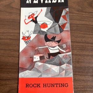 May include: A vintage Nevada travel brochure with a cartoon illustration of cowboys rock hunting. The brochure has a black top with the word "NEVADA" in white, and a red bottom with the words "ROCK HUNTING". The illustration is in black, white, and red.