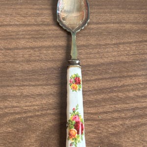 May include: A white ceramic mug with a black handle and the text "But First, Coffee" in a bold, black font. The mug is set against a blurred background, suggesting a cosy setting.