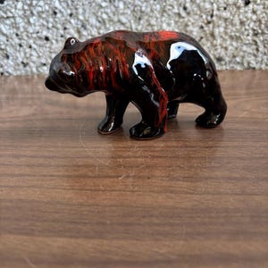 May include: A small ceramic bear figurine with a black and red marbled glaze.