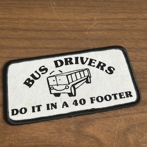 Könnte beinhalten: Weißer Patch mit schwarzem gesticktem Text und einem Cartoon-Bus. Der Text lautet "Bus Drivers Do It In A 40 Footer".