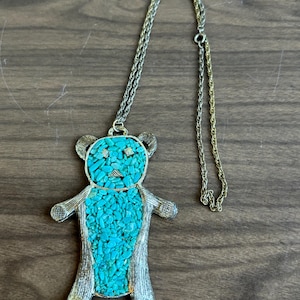 以下が含まれることがあります： ターコイズとシルバーのクマのペンダントネックレス。クマは小さなターコイズストーンで作られており、シルバーチェーンが付いています。