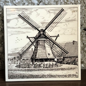 Peut inclure: Illustration en noir et blanc d'un moulin à vent avec le texte "Den Oever Molen. De Hoop" anno 1654. Le moulin à vent est entouré d'arbres et de maisons.
