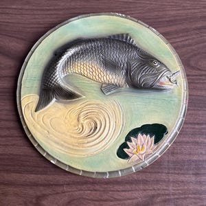 Puede incluir: Una taza de cerámica blanca con un asa negra y el texto "But First, Coffee" en negro y negrita. La taza está sobre una superficie de madera. La taza mide aproximadamente 10 cm de alto.