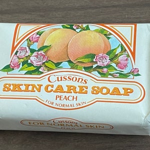 May include: A white bar of soap with a peach design and the text "Cussons Skin Care Soap Peach For Normal Skin" on the front.