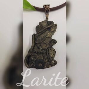 May include: A gold-colored pendant necklace featuring a detailed mouse figurine wearing a hat. The mouse is sitting on a round base and has a blue eye.