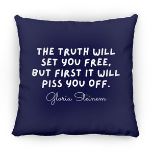 May include: A navy blue throw pillow with white text that reads "THE TRUTH WILL SET YOU FREE, BUT FIRST IT WILL PISS YOU OFF."  The text is in a handwritten font.  The author's name, "Gloria Steinem", is written in cursive below the quote.