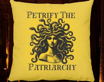 Könnte beinhalten: Gelbes Kissen mit einer Schwarz-Weiß-Illustration von Medusa, einer mythischen griechischen Figur mit Schlangenhaaren. Der Text "Petrify the Patriarchy" ist unter der Illustration gedruckt.